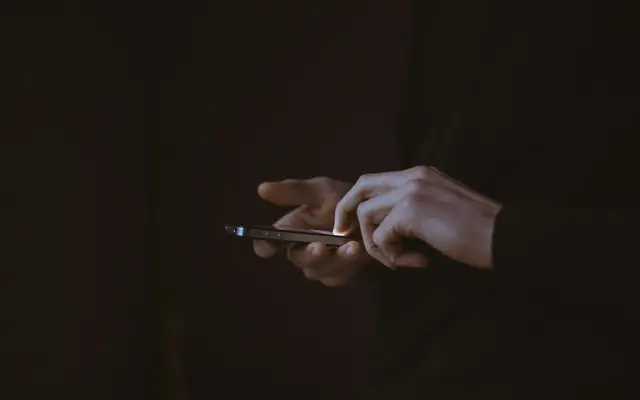 Mano con un celular en la oscuridad: abogado por amenazas