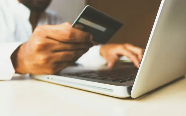 Persona con una tarjeta frente al notebook: abogado por estafa